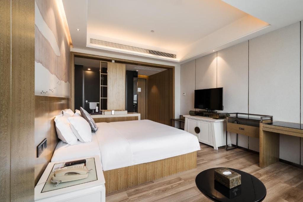 ein Hotelzimmer mit einem Bett und einem Fernseher in der Unterkunft Paco Hotel Shuiyin Road Guangzhou-Free bus Canton Fair in Guangzhou