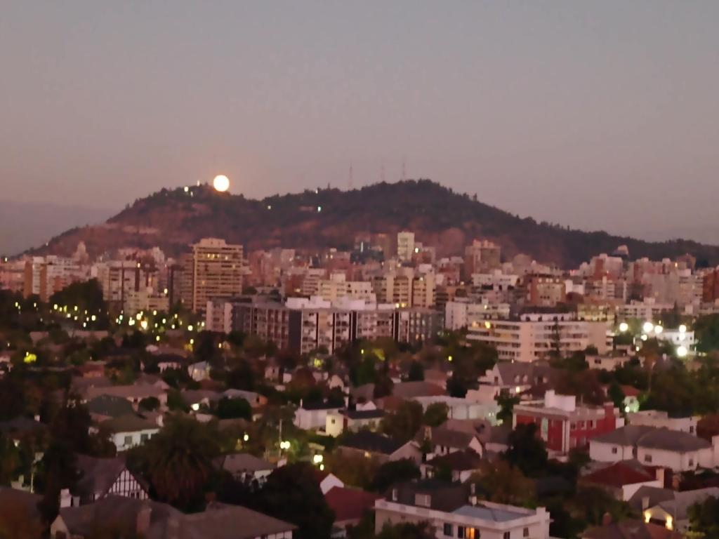 a view of a city at night with the moon at Habitación departamento Bilbao in Santiago