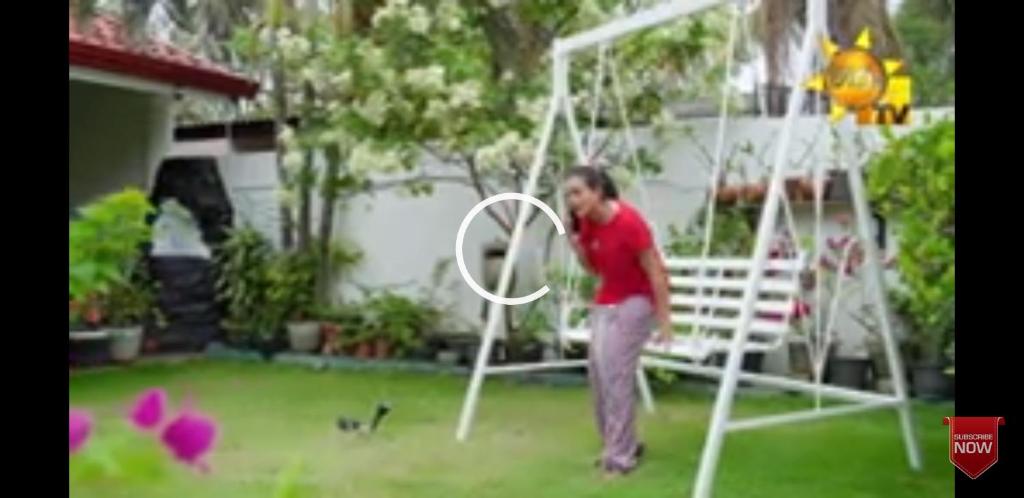 Una donna in piedi in un giardino che gioca con un cerchio di RM Holiday Home a Hikkaduwa