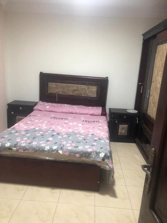 a bedroom with a bed with a pink comforter at شقة in Alexandria