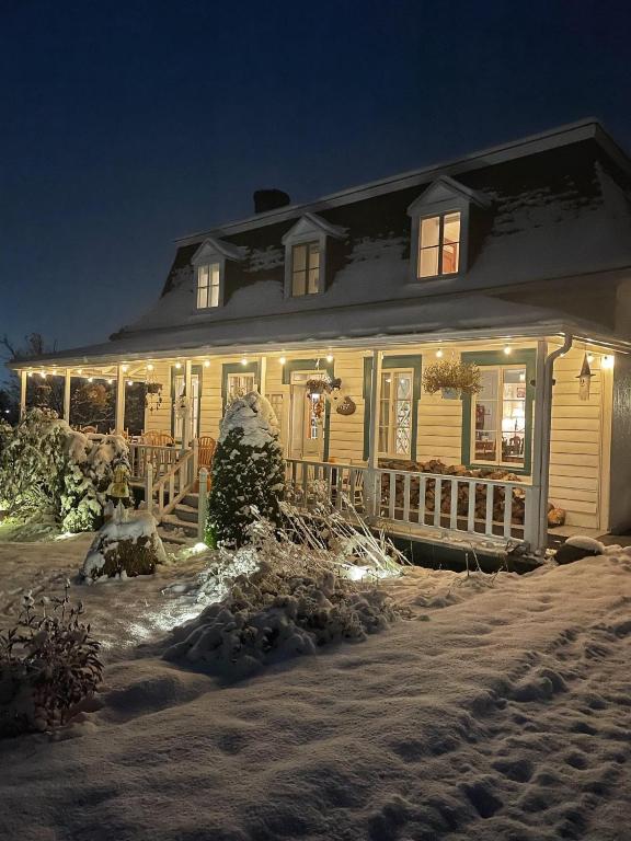 a house with christmas lights on it in the snow at Auberge musicale Pour un Instant in La Malbaie
