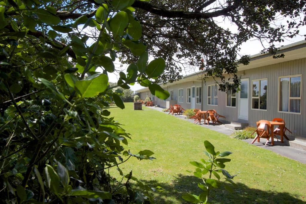 ein Haus mit einem Garten mit Stühlen und einer Liegewiese in der Unterkunft 252 Beachside Motels & Holiday Park in Hokitika