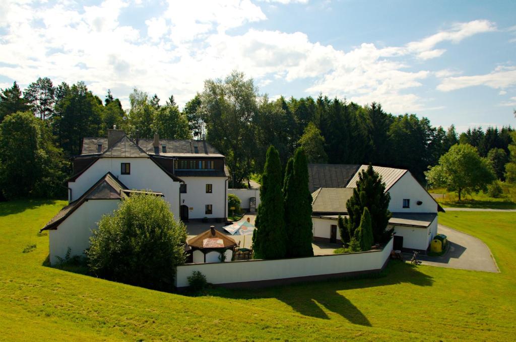 a large white house in a field with trees at Hotel a Hostinec Tálský mlýn in Žďár nad Sázavou