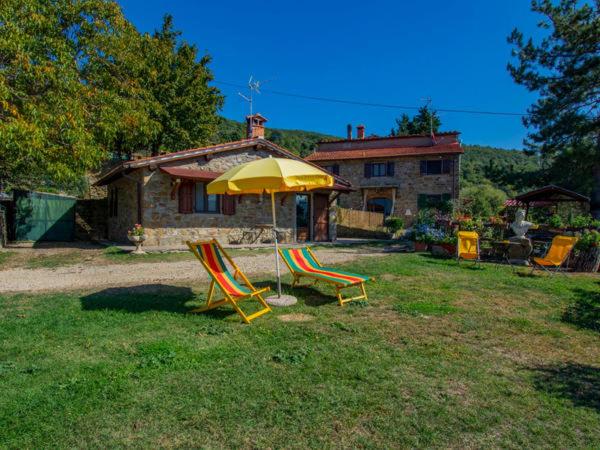 two lawn chairs and an umbrella in a yard at BeB Il Poderino Family Room in Dicomano