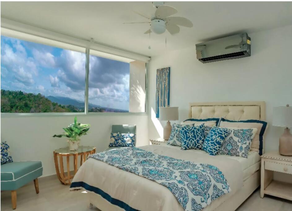 een slaapkamer met een bed en een groot raam bij Elegante apartamento en condominio cerca del aeropuerto 