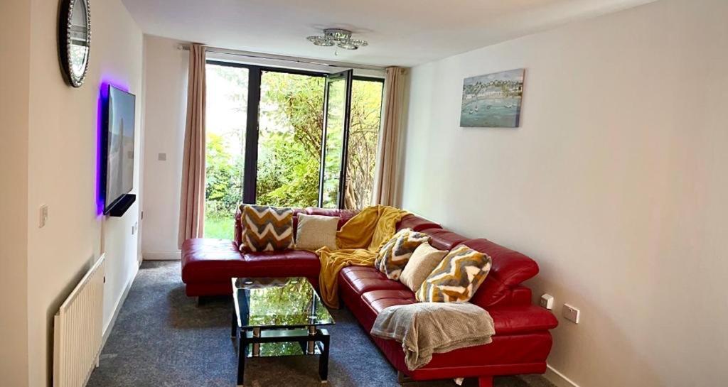 ein rotes Sofa im Wohnzimmer mit Fenster in der Unterkunft ARIEL LUXURY APARTMENT in London