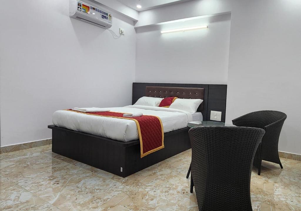 RāmanagaramにあるRoyal Residencyのベッドルーム1室(ベッド1台、椅子2脚、テーブル付)