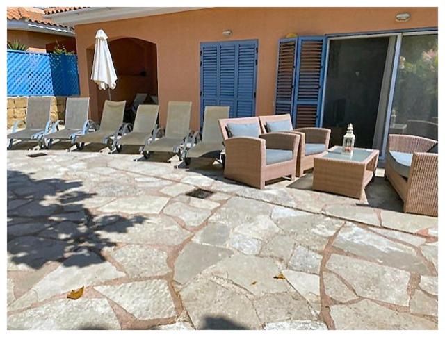 eine Gruppe Stühle und ein Sonnenschirm auf einer Terrasse in der Unterkunft Limnaria Gardens 6464 in Paphos City