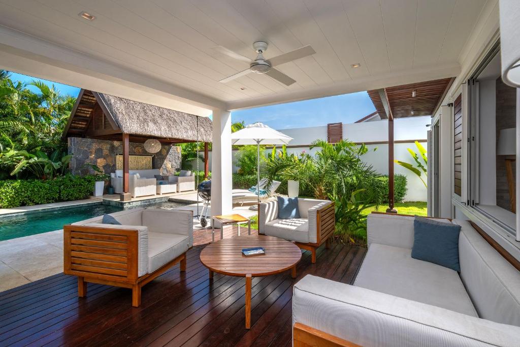 a living room with white furniture and a pool at VILLA LILOU, Splendide villa au centre de Grand Baie in Grand Baie