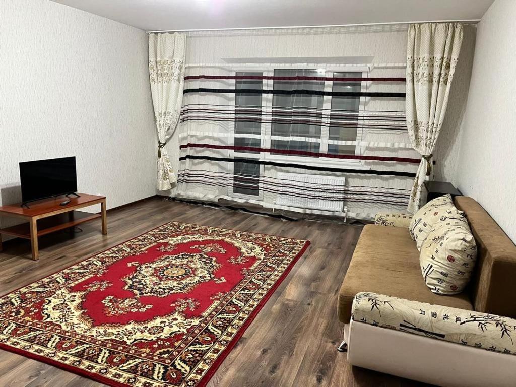 a living room with a couch and a red rug at Квартира in Karagandy