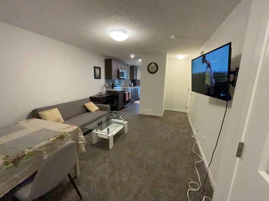 a living room with a couch and a flat screen tv at Brand New One Bedroom Suite in Calgary
