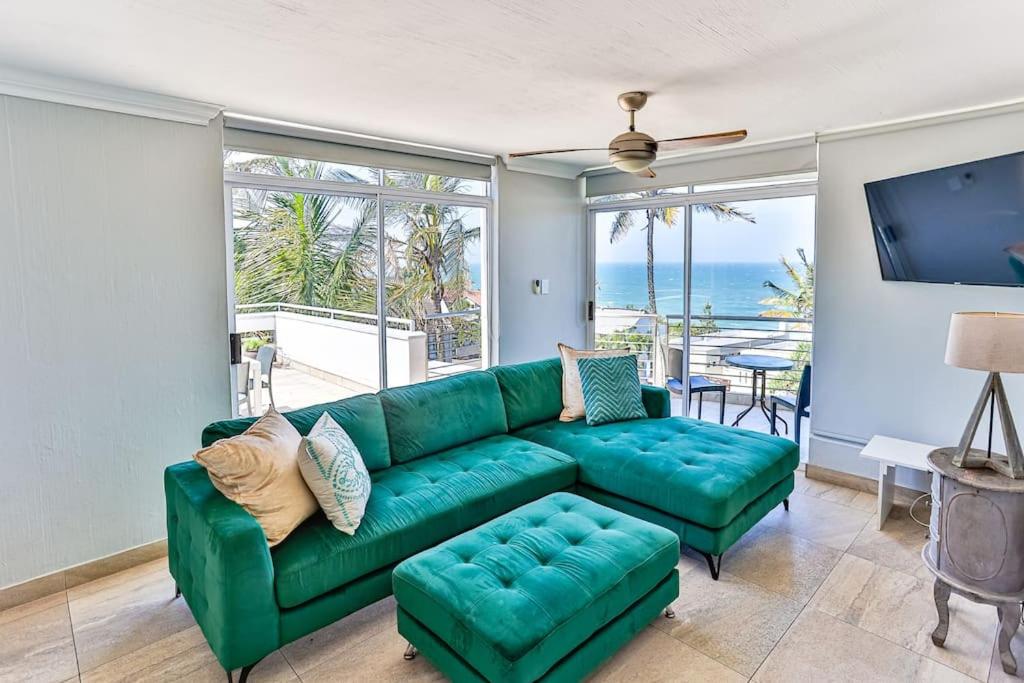 a living room with a green couch and a view of the ocean at Seaside 96 - Family only in Ballito