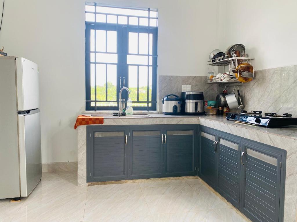 a kitchen with blue cabinets and a sink at Homestay Nhà Của Gạo in Bao Loc
