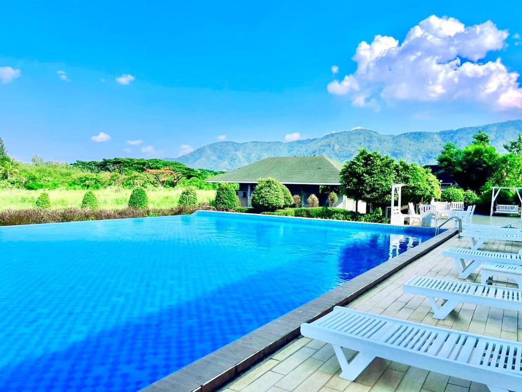 a swimming pool with chairs and mountains in the background at Aurora Resort Khao Yai in Mu Si