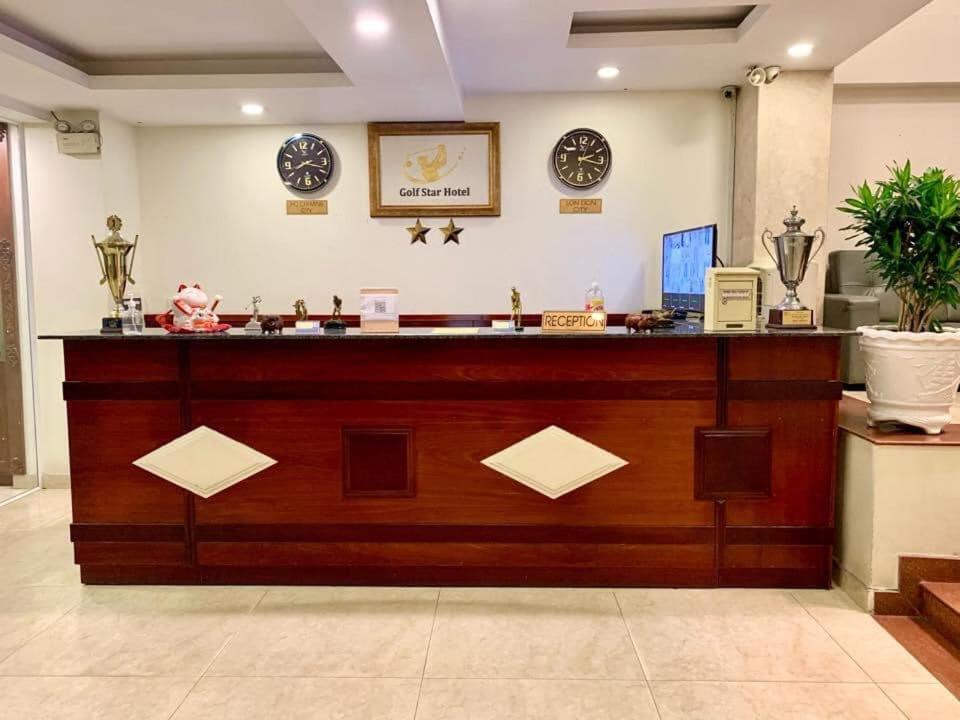 a lobby with a large wooden counter with clocks on the wall at Golf Star Hotel in Ho Chi Minh City