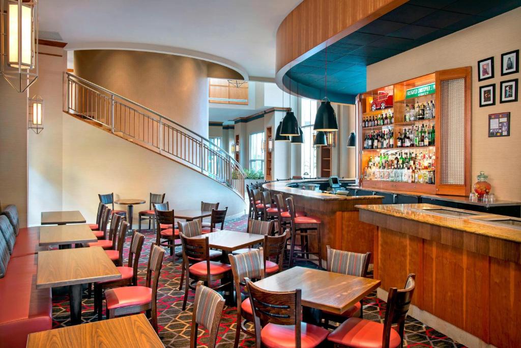 Four Points by Sheraton Melville Long Island في بلاينفيو: مطعم بطاولات وكراسي وبار