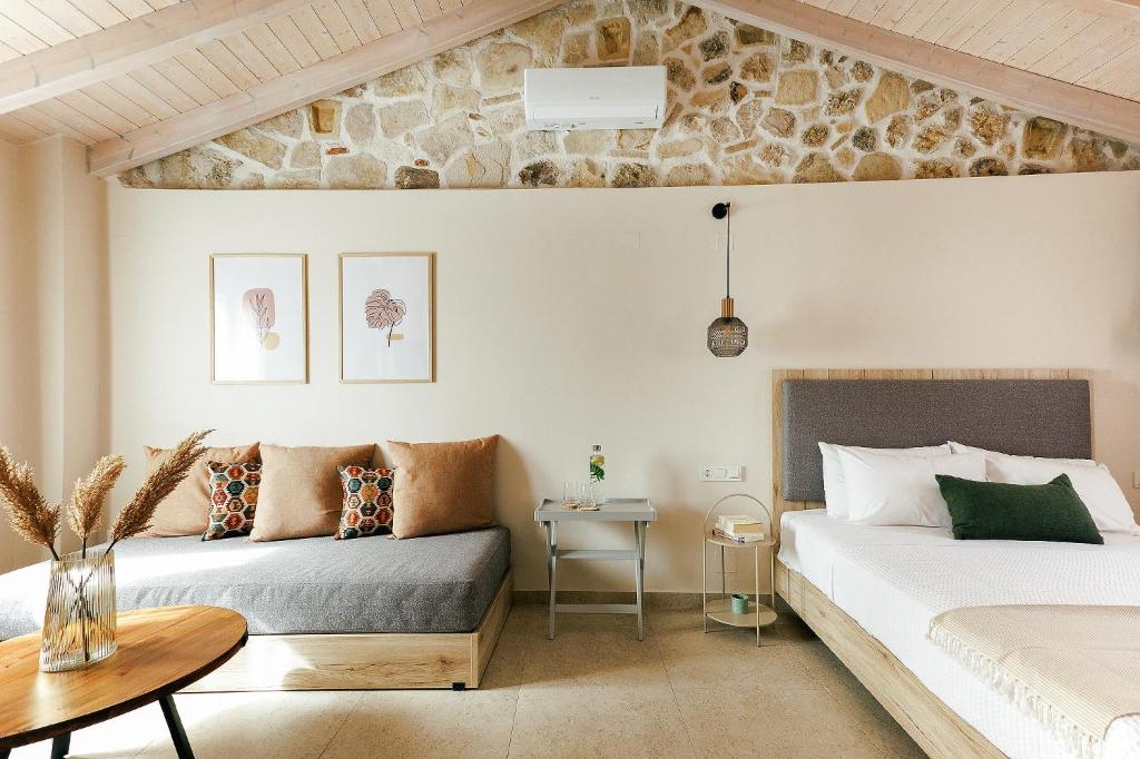 two beds in a bedroom with a stone wall at Limeria studios & maisonettes in Parga
