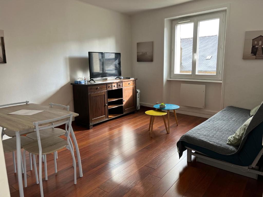 ein Wohnzimmer mit einem TV, einem Tisch und einem Sofa in der Unterkunft Dinan - appartement centre ville in Dinan