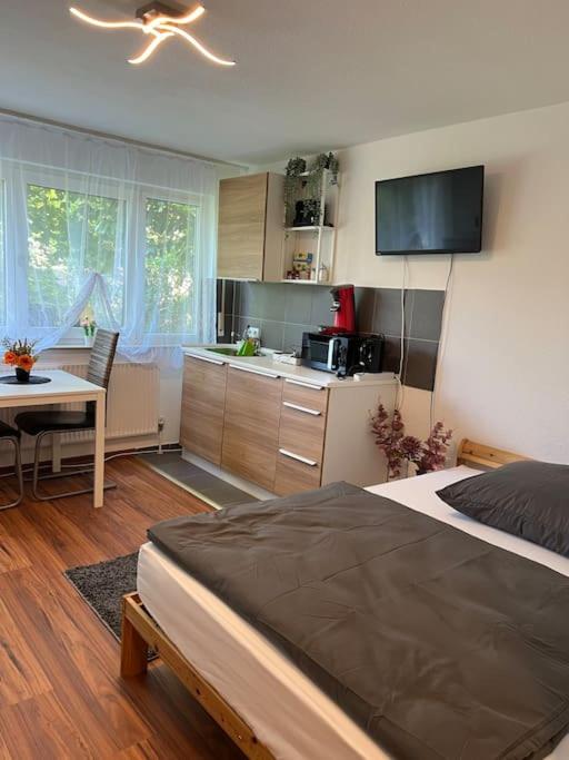 a bedroom with a bed and a table and a kitchen at Apartment (2) am Stuttgarter Flughafen / Messe in Leinfelden-Echterdingen