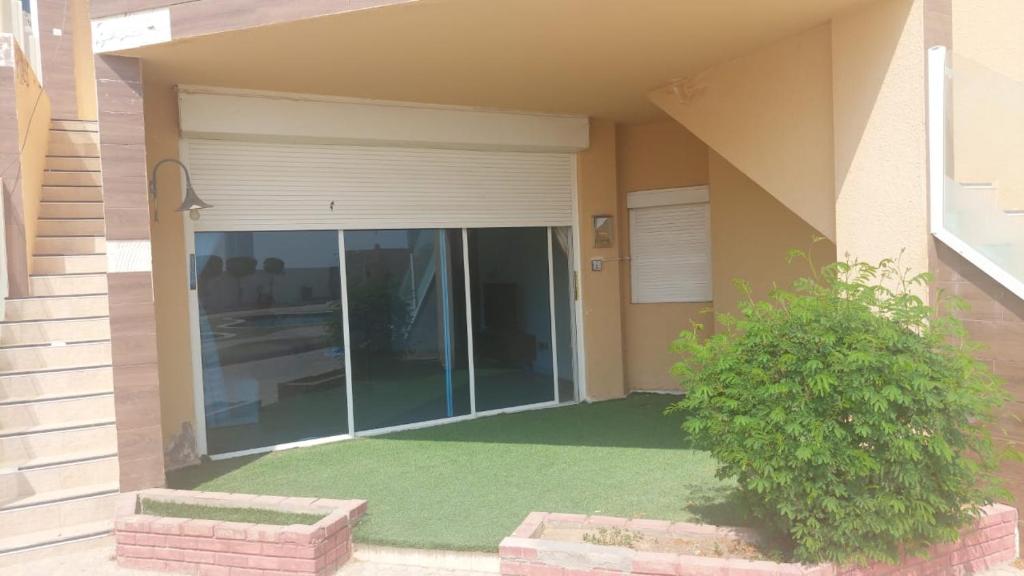 a house with a glass door with a green lawn at شاليه ارض السعاده 1 in Obhor