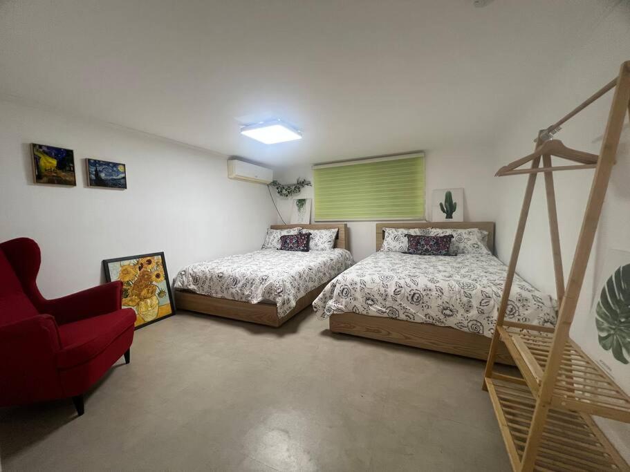 sypialnia z 2 łóżkami i czerwonym krzesłem w obiekcie Hongdae HK Stay w Seulu