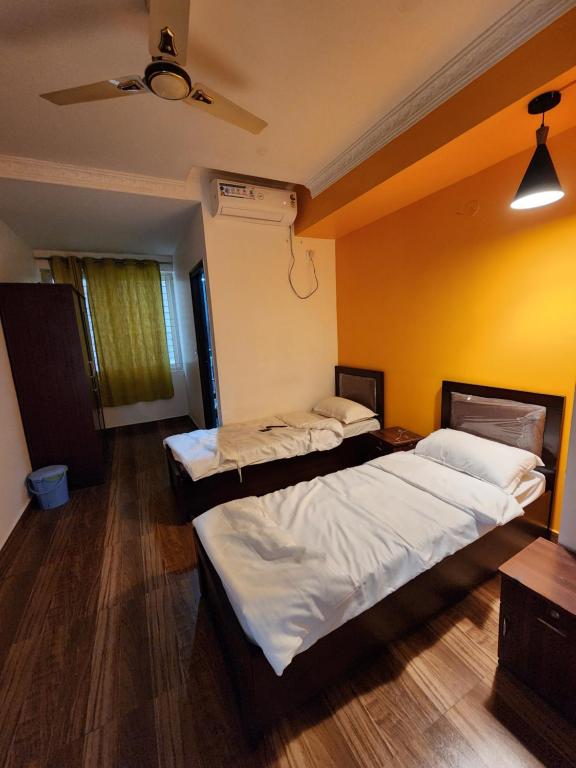 Duas camas num quarto com uma parede amarela em Royal Colive & Suits em Bangalore
