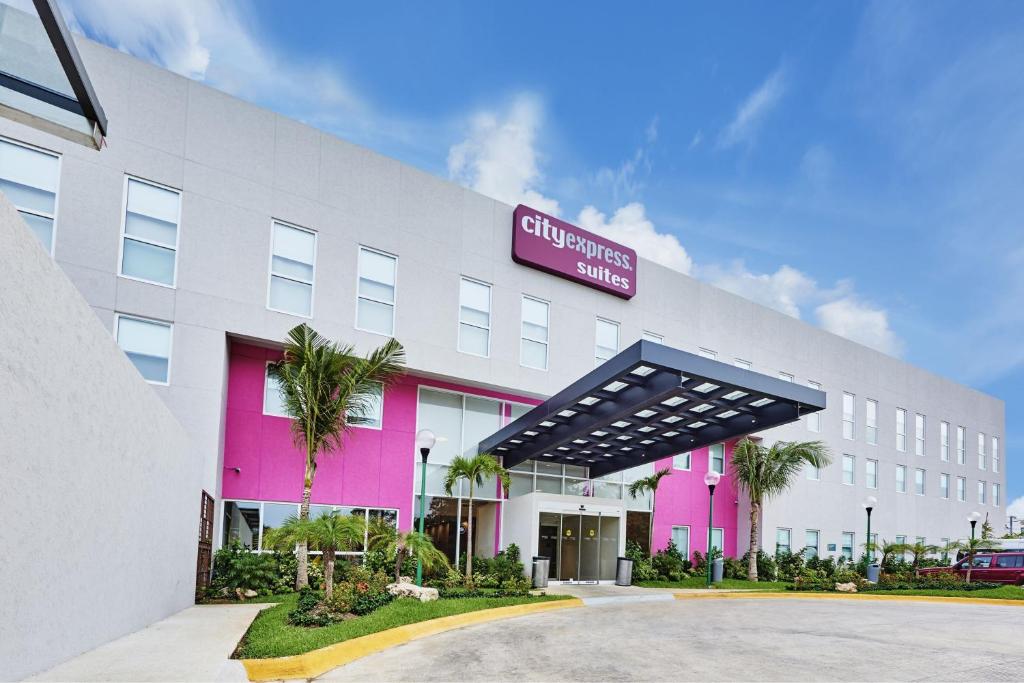 un edificio blanco y rosa con un cartel en él en City Express Suites by Marriott Playa del Carmen, en Playa del Carmen