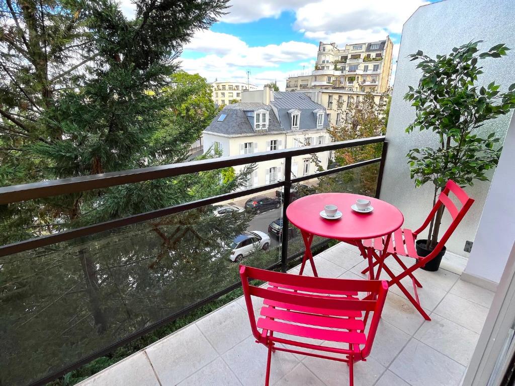d'une table rouge et de deux chaises sur un balcon. dans l'établissement le studio Molitor, à Boulogne-Billancourt