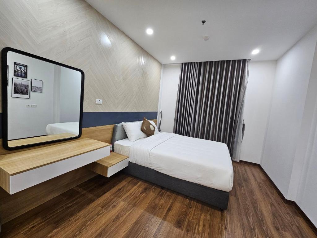ein Schlafzimmer mit einem Bett und einem großen Spiegel in der Unterkunft Serviced apartment with pool- Greenpearl Bắc Ninh in Hòa Ðình