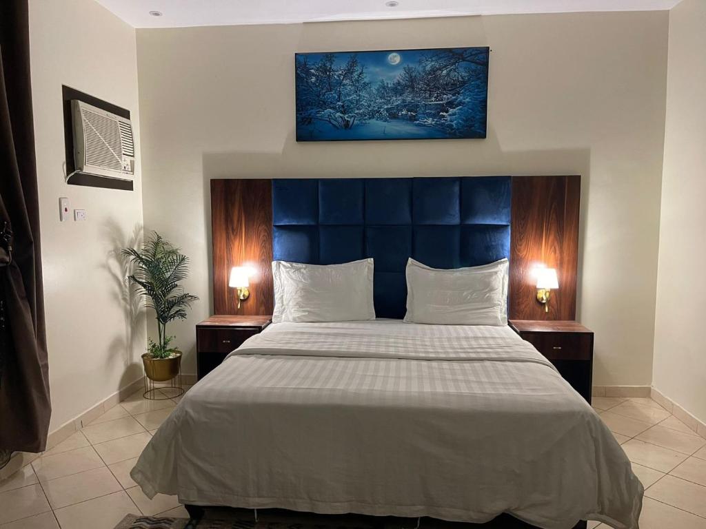 a bedroom with a large bed with a blue headboard at فخامة المصيف للشقق المخدومة 2 in Taif