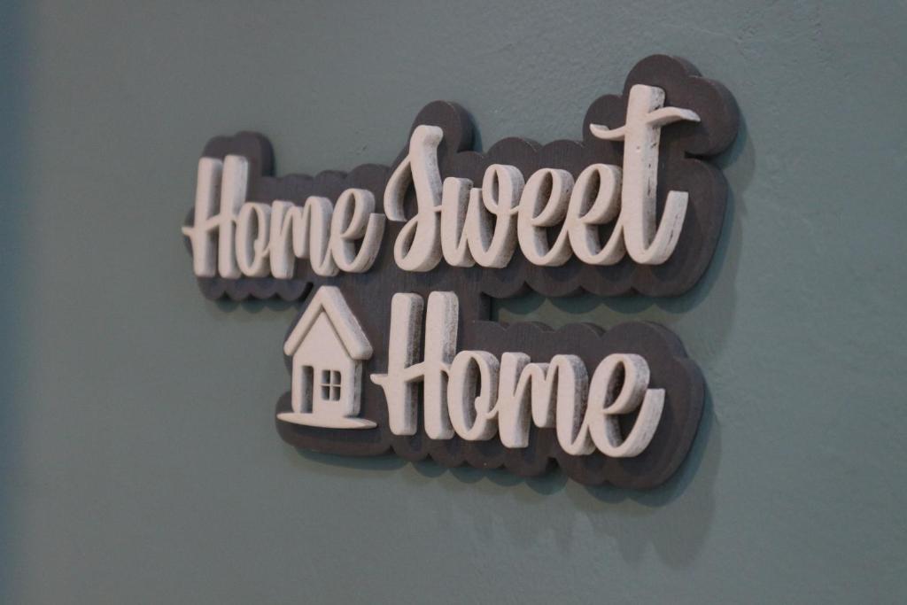 Una señal que dice hogar dulce hogar con una casa en Pomah Guest House, en Alastuwo