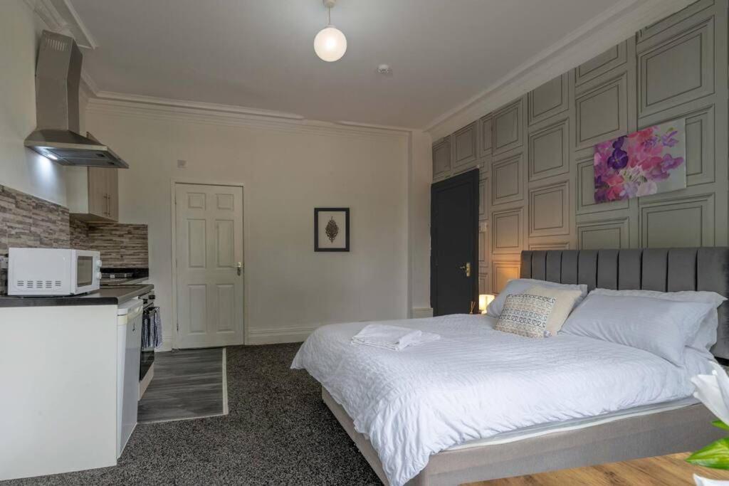 a bedroom with a white bed and a kitchen at City Studio: Studio Suite 2 in Parkside