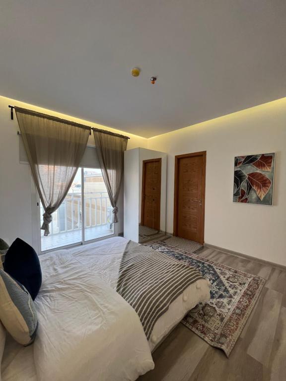 a bedroom with a large bed with a large window at Your home 2 in Jeddah