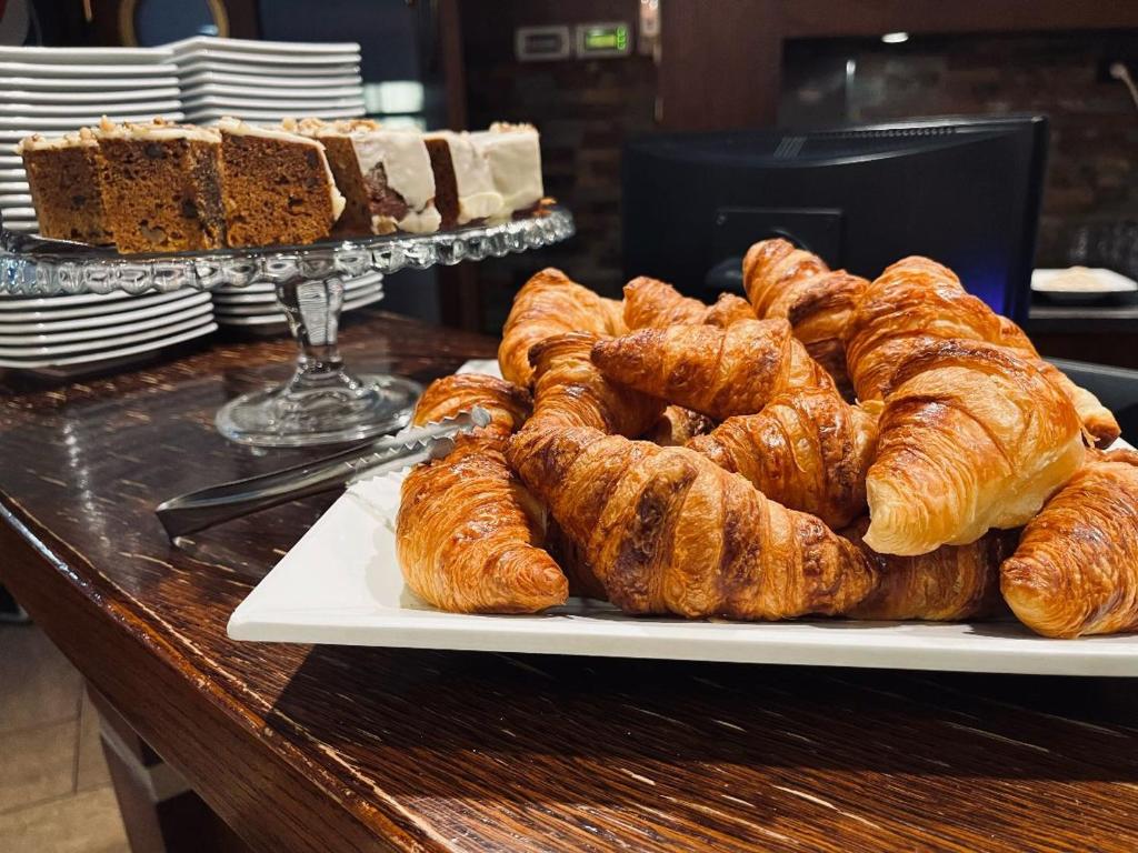un tavolo con un piatto di croissant e altri prodotti da forno di Amber Hotel a Danzica