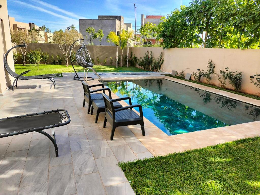a swimming pool with chairs and benches in a yard at Marrakech Villa du Golfeur familles uniquement in Marrakesh