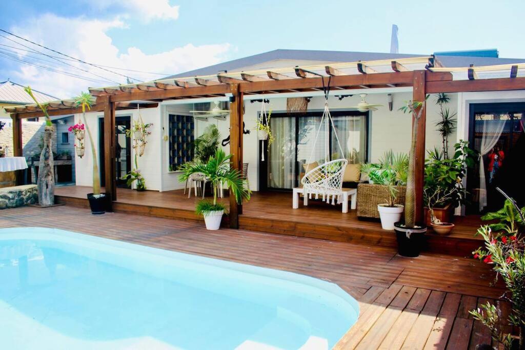 een huis met een zwembad op een houten terras bij Villa Terol, à proximité de l’océan in Saint-Paul