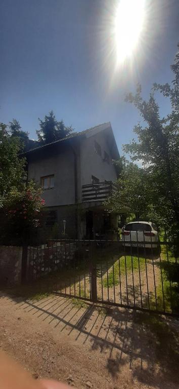 a house with the sun shining behind a fence at Misevici vikendica in Sarajevo