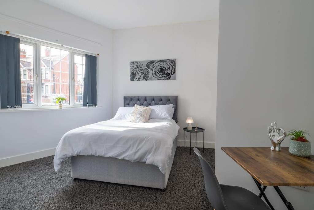 a white bedroom with a bed and a wooden table at Cosy City: Studio Suite 7 in Parkside