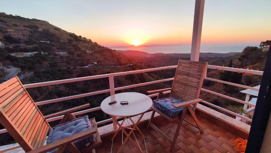 a balcony with a table and chairs and the sunset at Enjoy sunset from a wonderful traditional studio-Melina in Ioulis