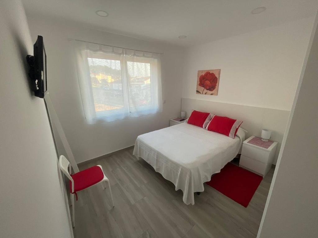 Un dormitorio con una cama con almohadas rojas y una ventana en LOFT AS CASETAS PEREGRINOS, en Rosal