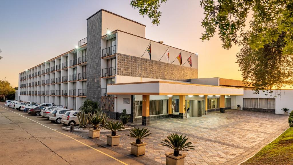 um hotel com carros estacionados num parque de estacionamento em African Sky Ermelo Inn em Ermelo