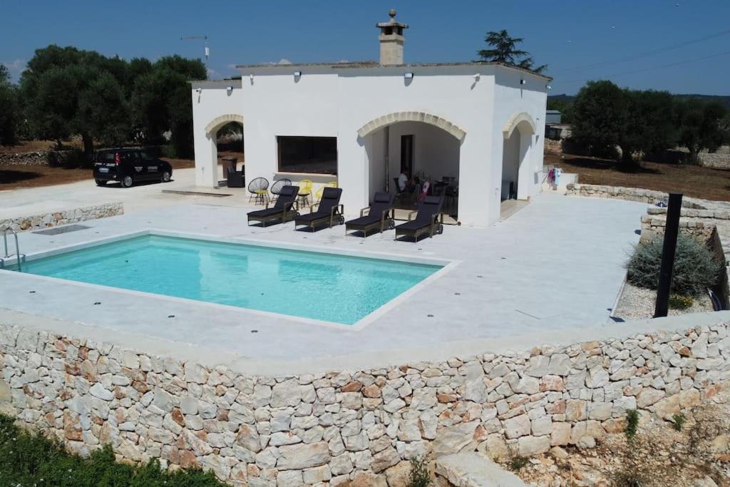 a villa with a swimming pool and a stone wall at Villa Dolce Far Niente Ostuni in Ostuni
