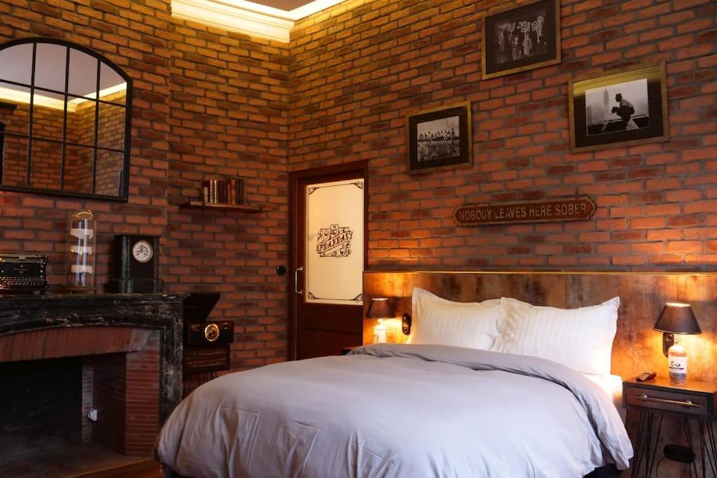 a bedroom with a bed and a brick wall at 35 SPEAKEASY - Ambiance PUB Anglais Centre Ville avec Parking in Reims