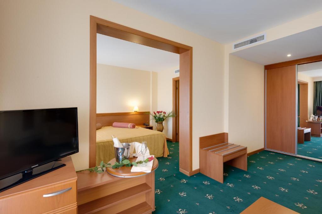 a hotel room with a television and a bedroom at Hotel Palas in Mamaia