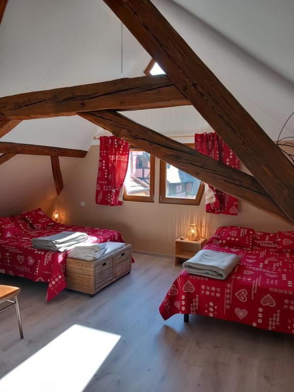 a attic room with two beds and red sheets at Gite Schlossberg in Colmar