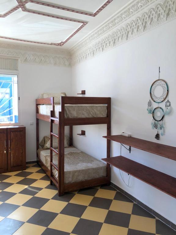 a room with bunk beds and a checkered floor at TOODA House in Imsouane