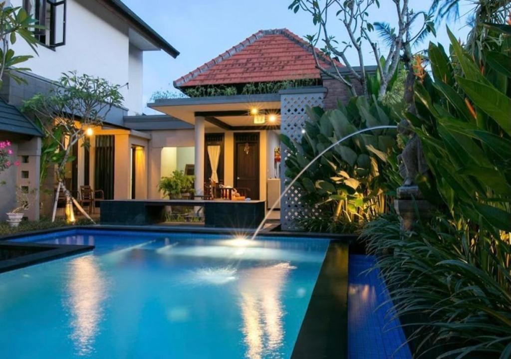 a swimming pool in front of a house at Meilds Property Kuta in Kuta