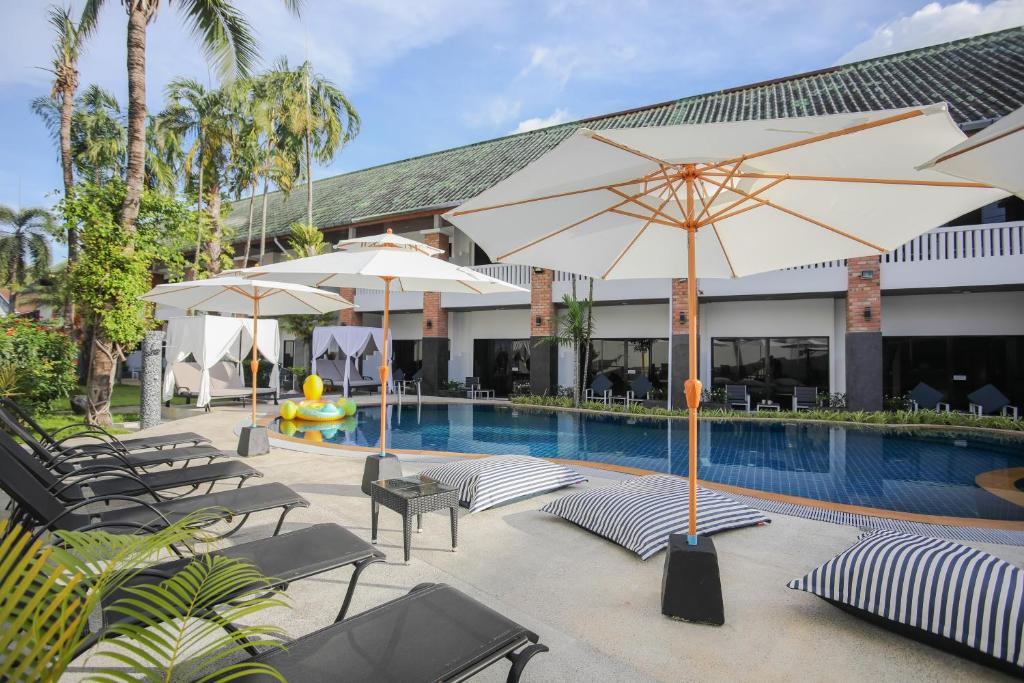 una piscina con sillas y sombrillas junto a un complejo en ETK Patong Resort, en Patong Beach