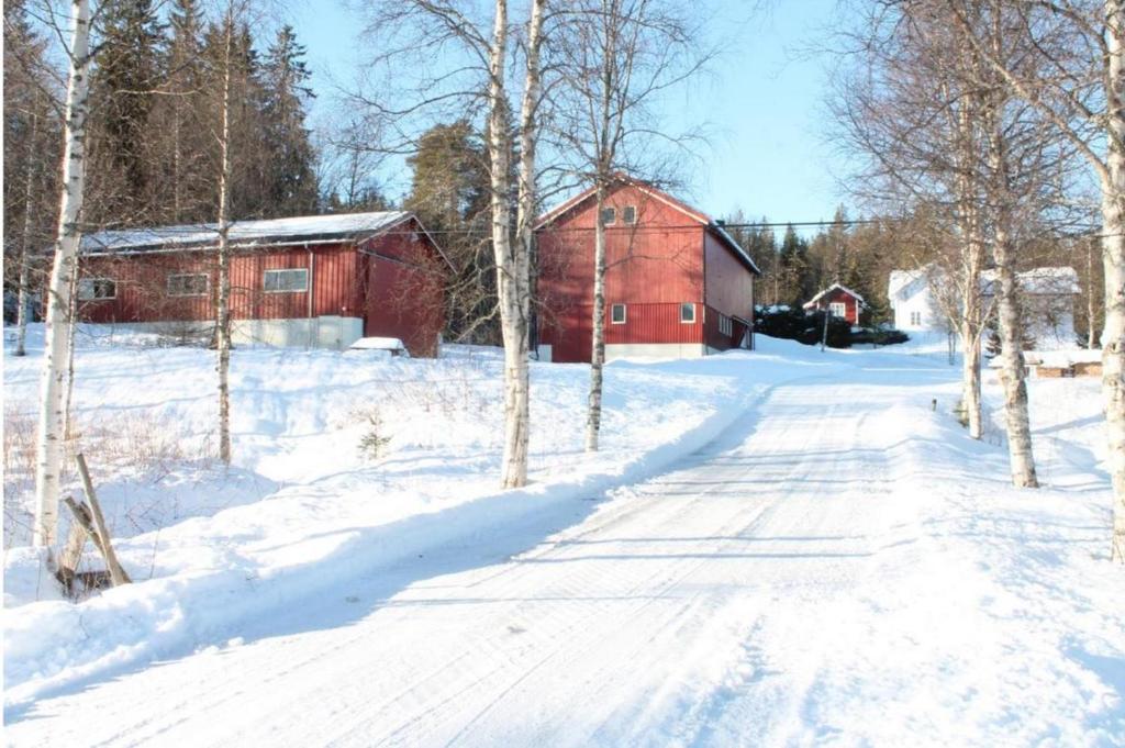 a snow covered road next to a red barn at Feriested i Tørberget in Tørberget