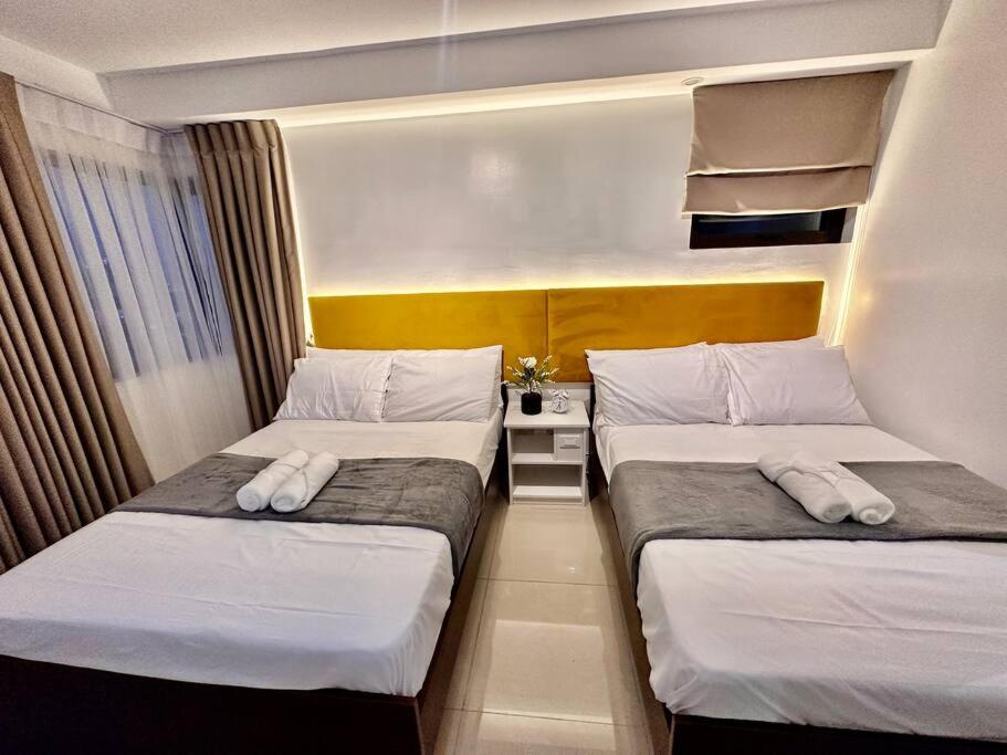 duas camas num pequeno quarto com em Hotel Living,The Persimmon double beds 4pax (904) em Cebu